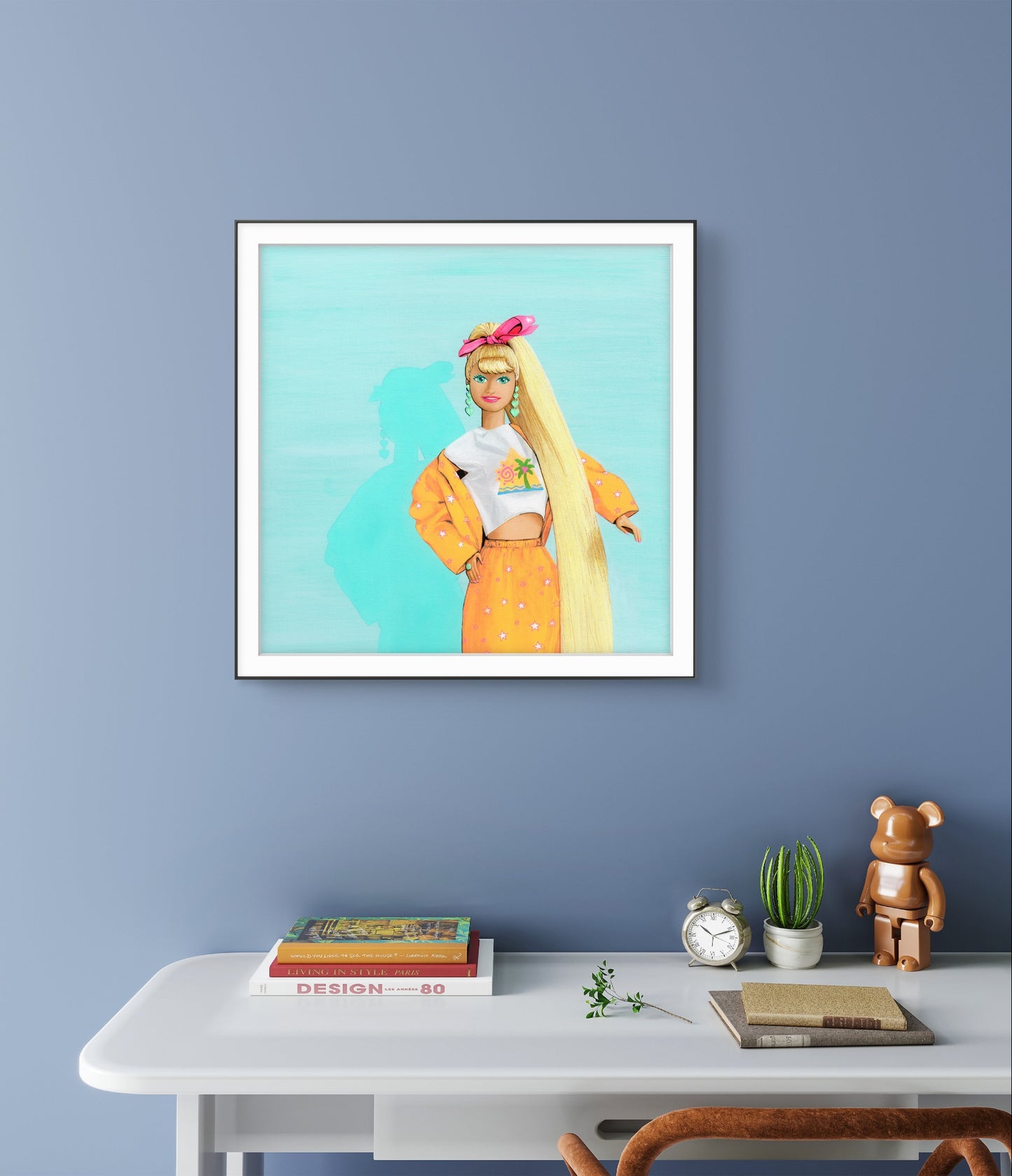 Framed artwork of a woman with long hair on a blue wall above a white desk.