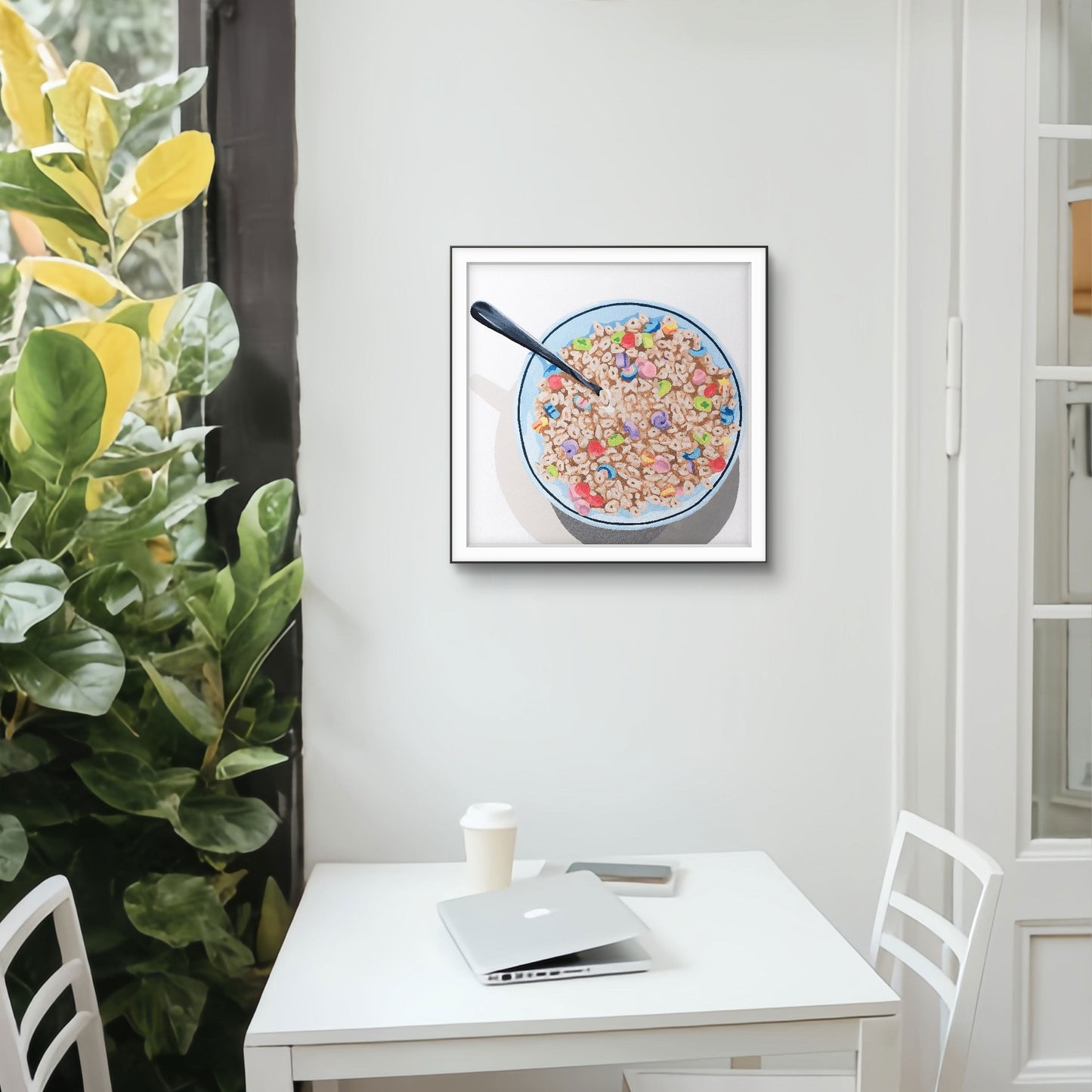 Framed artwork of a bowl of cereal with a spoon on a white wall above a desk.