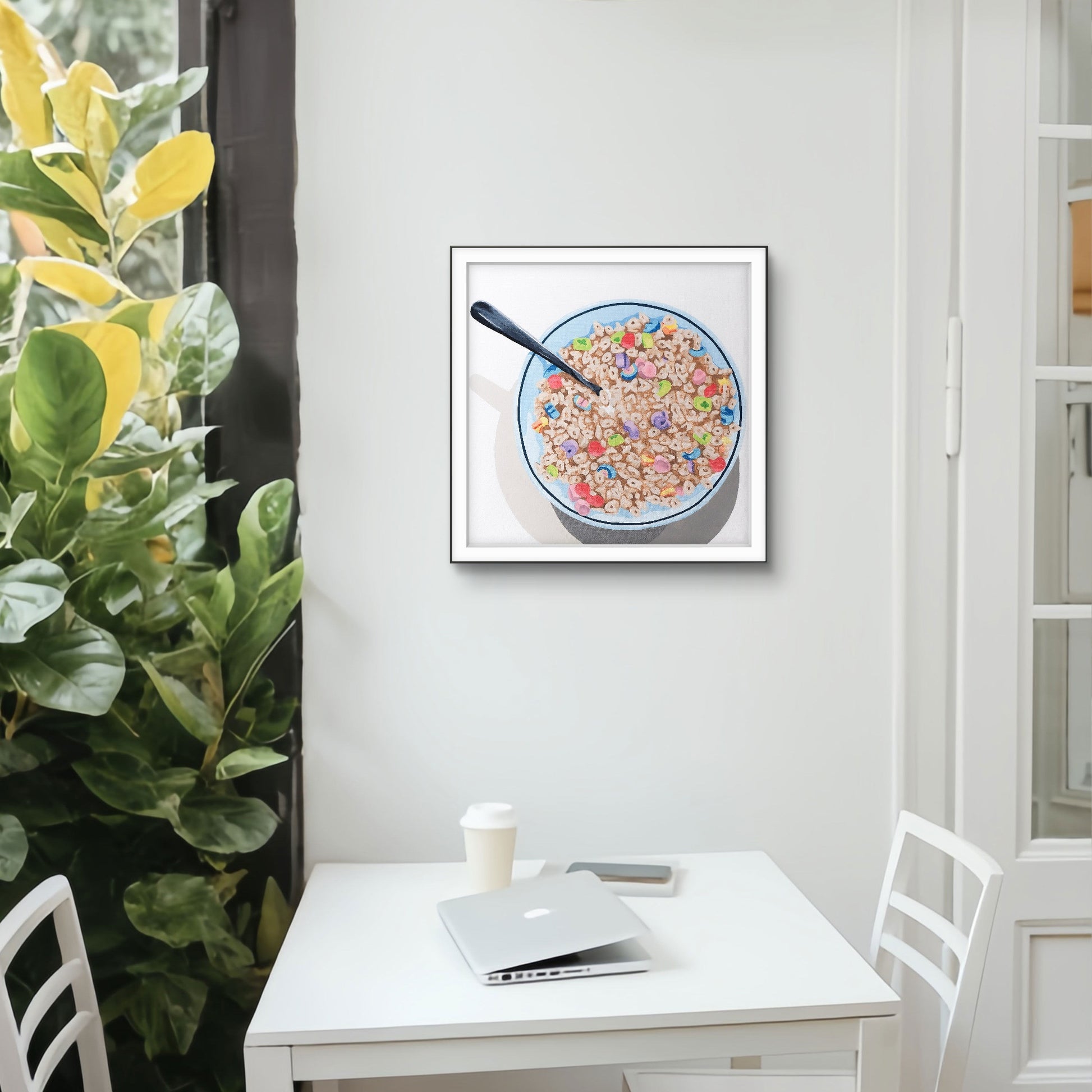 Framed artwork of a bowl of cereal with a spoon on a white wall above a desk.