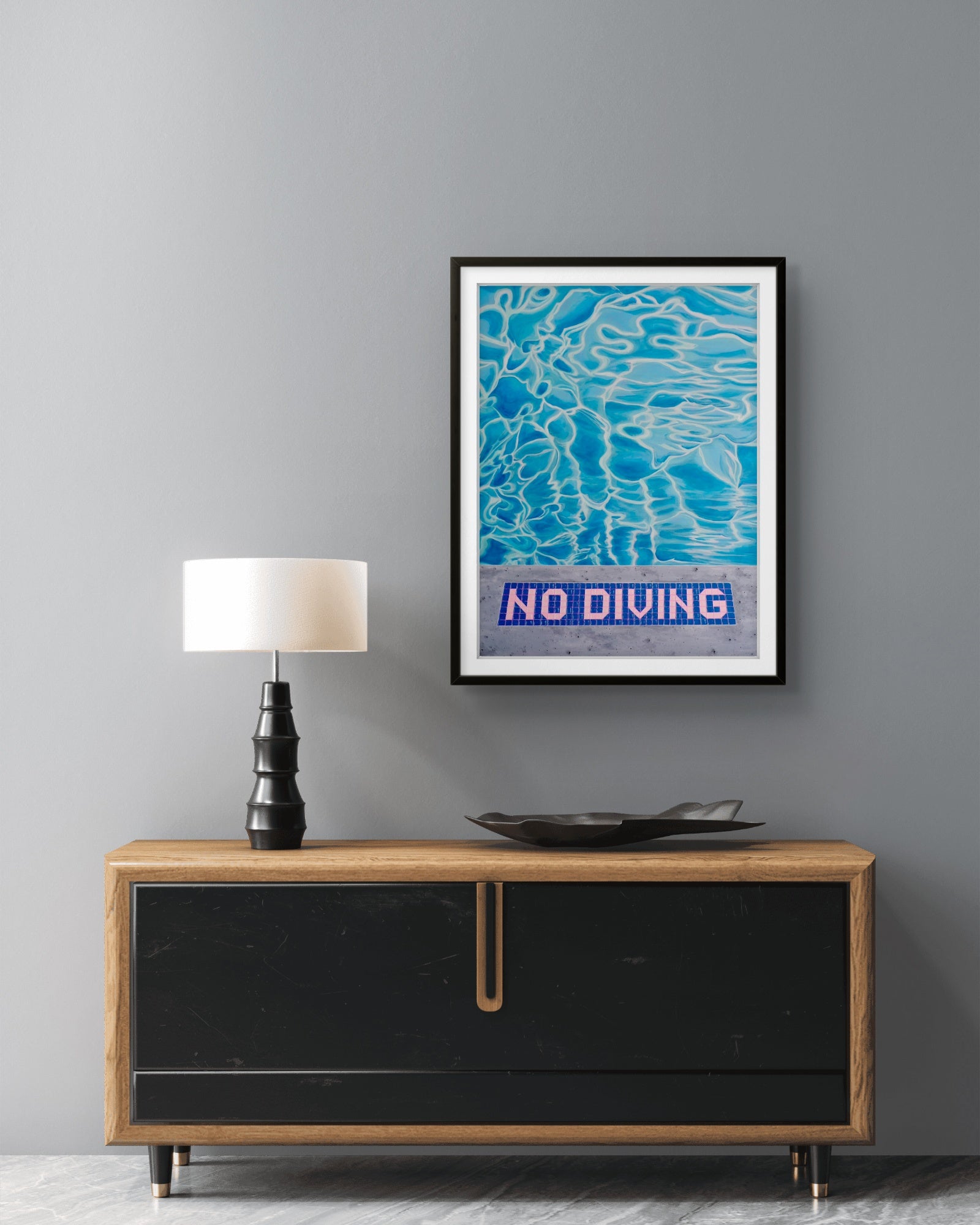 Framed 'No Diving' poster above a wooden console table with a lamp and decorative bowl.