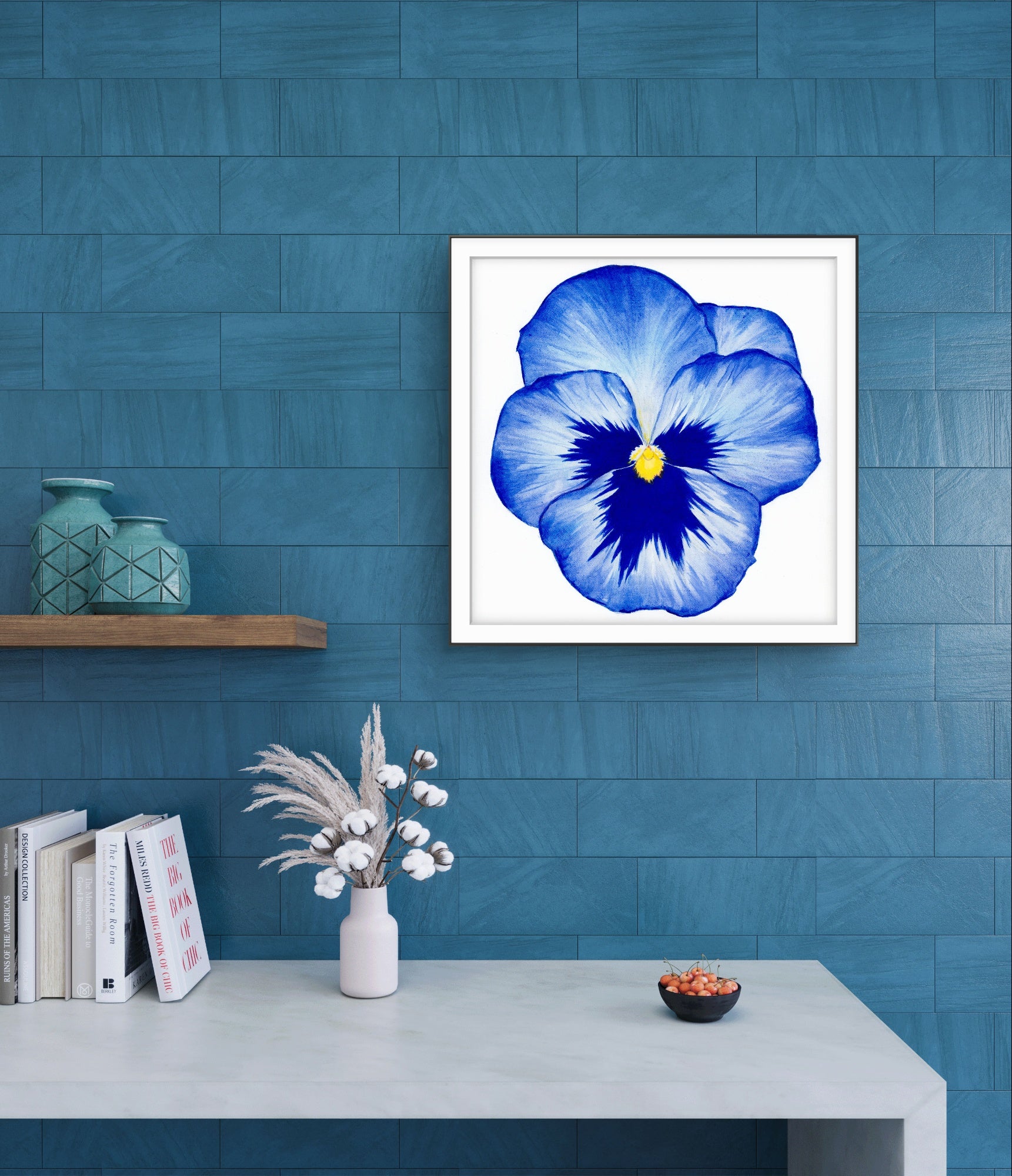 Framed blue flower print on a blue wall with decorative items below.