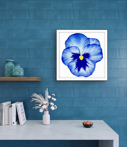 Framed blue flower print on a blue wall with decorative items below.