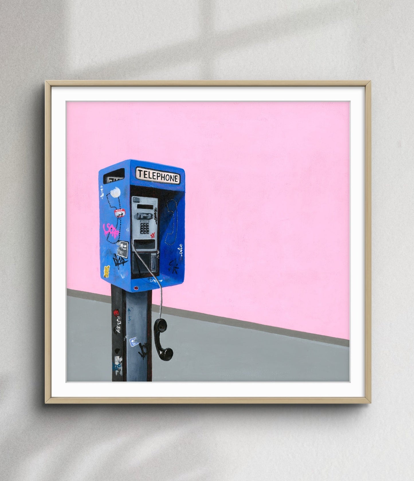 Framed artwork of a blue telephone booth against a pink background